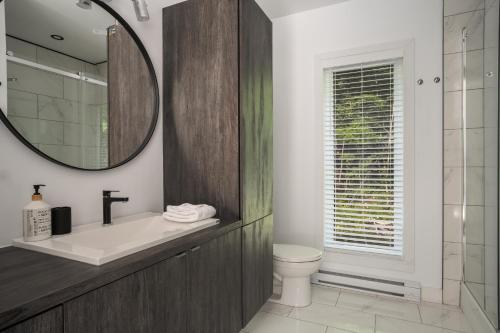 a bathroom with a sink and a toilet and a mirror at Starry Tremblant l Design Glass View Cabin Spa Lake in Saint-Rémi-dʼAmherst