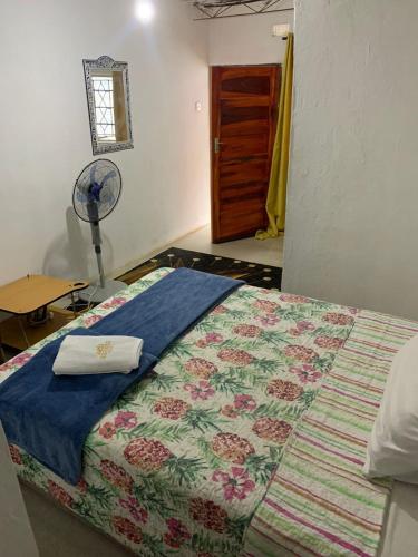 a bedroom with a bed with a blanket and a fan at WINZMAR LODGE in Lusaka