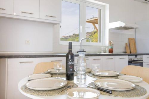 a white kitchen with a table with plates and a bottle of wine at Alethea's Sea View Apartment in Kalamaki