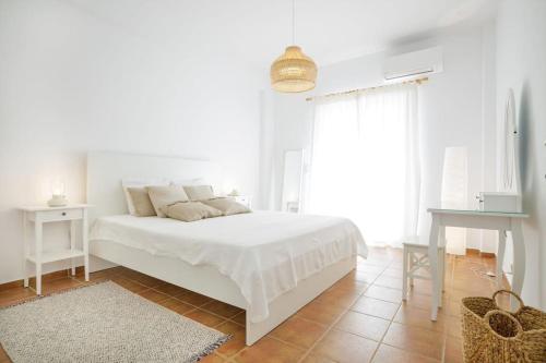 a white bedroom with a white bed and a table at Alethea's Sea View Apartment in Kalamaki