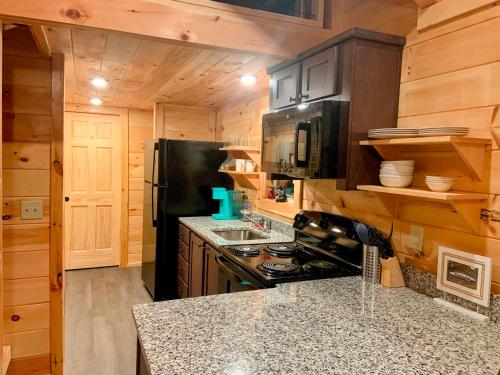 eine Küche mit einem schwarzen Kühlschrank und einem Herd in der Unterkunft Cozy Bear Mountain Tiny House in Travelers Rest