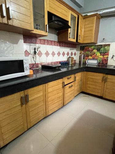 a kitchen with wooden cabinets and a microwave at Urban Oasis in Zirakpur