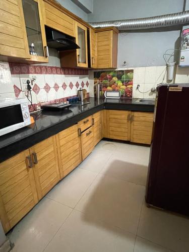 a kitchen with wooden cabinets and a microwave at Urban Oasis in Zirakpur