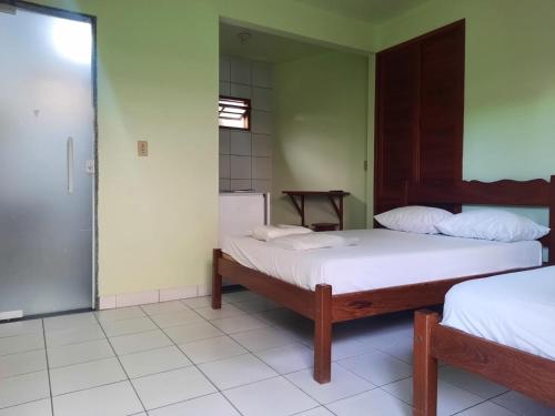a bedroom with two beds and a door to a bathroom at Pousada da Nalva in Rio das Ostras