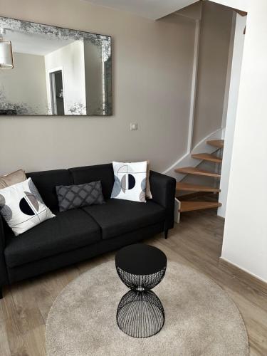 a living room with a black couch and a table at Hôtel Échappée en Baie - Parking privé gratuit dont forfaits bornes électriques réservable in Saint-Valery-sur-Somme