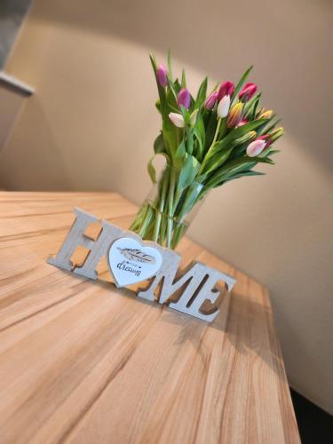 a vase of pink flowers sitting on a table with a sign at Ferienwohnungen Abendsonne - 8 Gehminuten zum EP in Rust