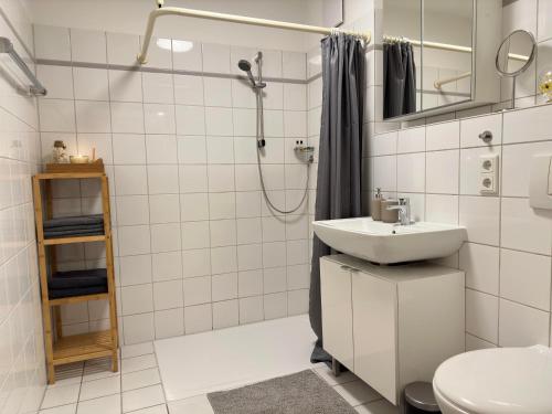 y baño blanco con lavabo y ducha. en Moderne Wohnung, zentral gelegen en Bielefeld