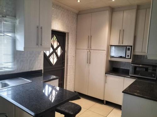 a kitchen with white cabinets and a black counter top at Restwell Accommodation in Pietermaritzburg