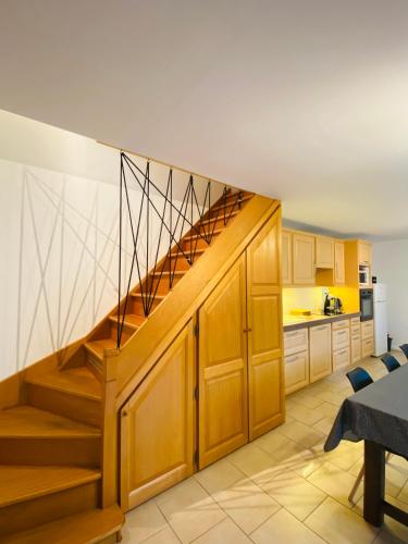 a kitchen with wooden cabinets and a staircase at La maison Girafe in Faverolles