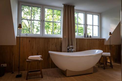 La salle de bains est pourvue d'une grande baignoire blanche et de fenêtres. dans l'établissement Spreewald Chalet, à Kolonie