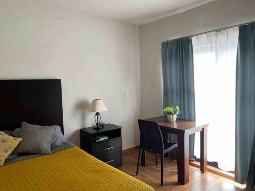 a bedroom with a bed and a desk and a table at Confortable Apartmento in Guanajuato