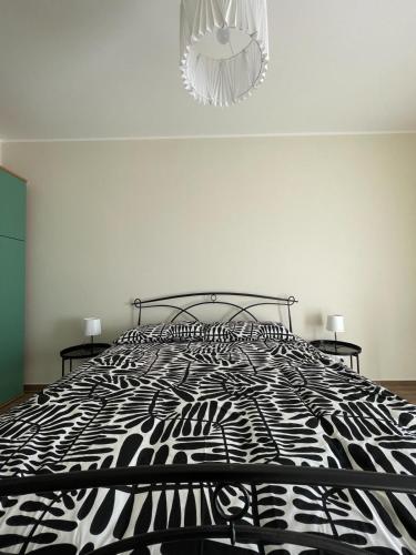 a black and white bed in a bedroom with a chandelier at Residence Guttuso in Gravina di Catania