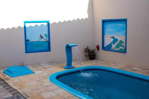 a pool with a water fountain in a room with paintings at Pousada Rincão Paraíso in Barreirinhas