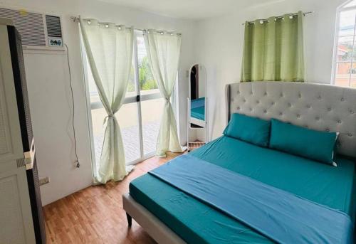Schlafzimmer mit einem Bett mit blauer Bettwäsche und einem Fenster in der Unterkunft Camella Mabini Cabanatuan in Cabanatuan