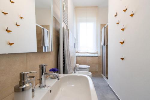 ein Badezimmer mit einem Waschbecken und einem WC mit Schmetterlingen an der Wand in der Unterkunft Arona 85 - Cozy apartment - Wi-Fi - NETFLIX in Arona