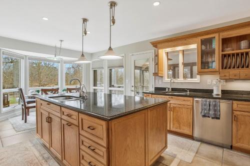 a large kitchen with wooden cabinets and a large island at Gorgeous Creek Side Ranch-Style Estate With Dock in Grasonville