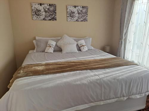 a bedroom with a white bed with pillows and a window at Elim self catering in Fisherhaven
