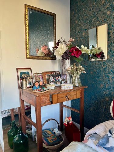 een kamer met een tafel met bloemen en een spiegel bij Chez Toinette in Bretteville-sur-Odon
