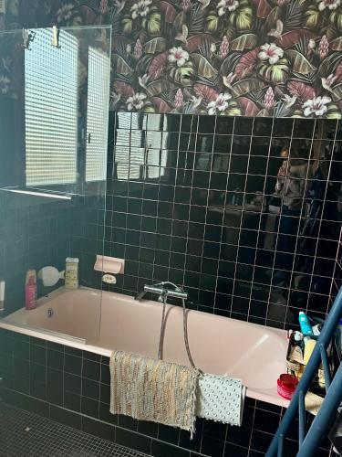 a bath tub in a bathroom with green tiles at Chez Toinette in Bretteville-sur-Odon