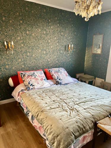 een slaapkamer met een bed met een groene muur bij Chez Toinette in Bretteville-sur-Odon