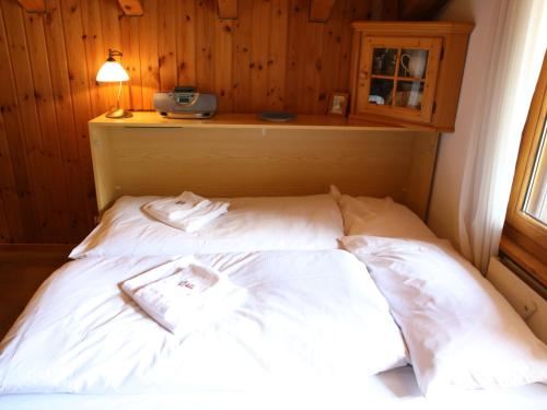a bed with white sheets and a book on it at Monte Rosa Apartments Täsch in Täsch