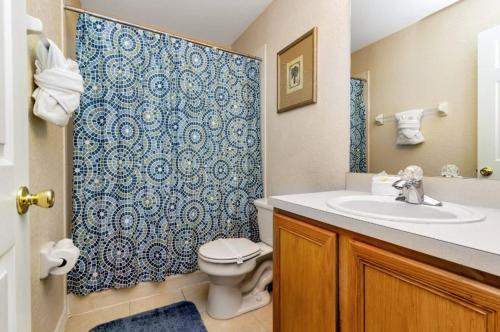 a bathroom with a toilet and a sink with a blue shower curtain at Villas at Regal Palms-4 Bedroom3.5 bath Townhouse in Davenport