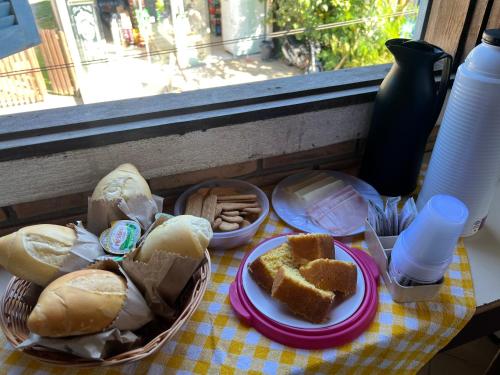 a table with bread and pastries on a table with a window at Flat Trindade in Trindade