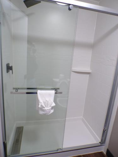 a shower with a glass door with a towel at Luxor Inn & Suites, a Travelodge by Wyndham in Elkins