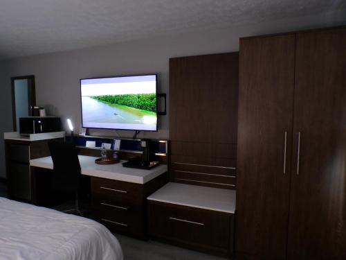a bedroom with a bed and a desk with a television at Luxor Inn & Suites, a Travelodge by Wyndham in Elkins