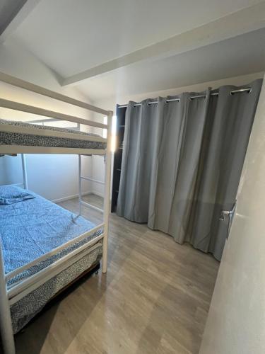een slaapkamer met 2 stapelbedden en gordijnen bij Maison avec jardin in Le Grau-du-Roi
