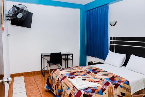 Zentrico Hotel في تشيكلايو: غرفة نوم بسرير وطاولة ومكتب