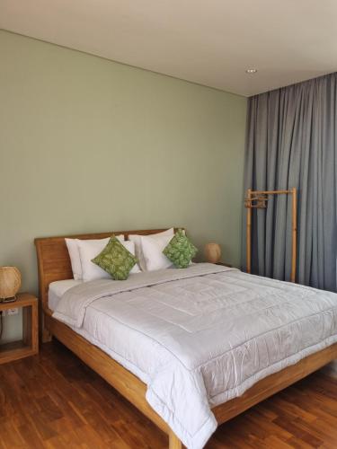 1 dormitorio con 1 cama grande con almohadas verdes en Villa Capella, en Canggu