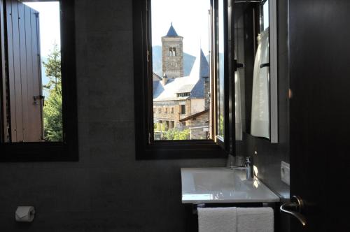 een badkamer met een wastafel en een raam met een klokkentoren bij Casa Rural La Comella in Tirvia