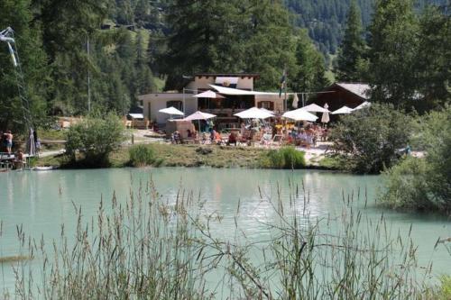 a restaurant with tables and umbrellas next to a lake at Monte Rosa Apartments Täsch in Täsch