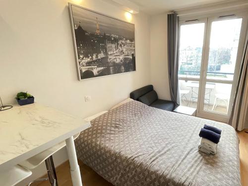 a bedroom with a bed and a table and a window at Exclusive Private Apartment by Warilco - Pleyel 25 m2 - À 1 minute de la station métro Carrefour Pleyel in Saint-Denis