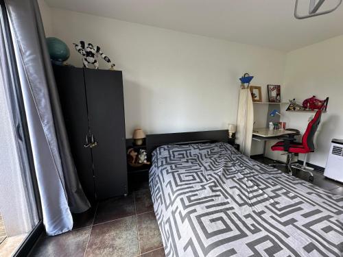 ein Schlafzimmer mit einem Bett, einem schwarzen Schrank und einem Schreibtisch in der Unterkunft chambre équipée in Panazol