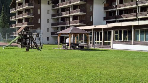 a playground in front of an apartment building with a playground at Monte Rosa Apartments Täsch in Täsch