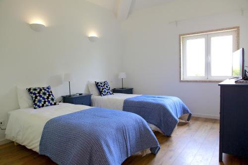 1 dormitorio con 2 camas y ventana en Quinta da Caldeireira, en Rosmaninhal