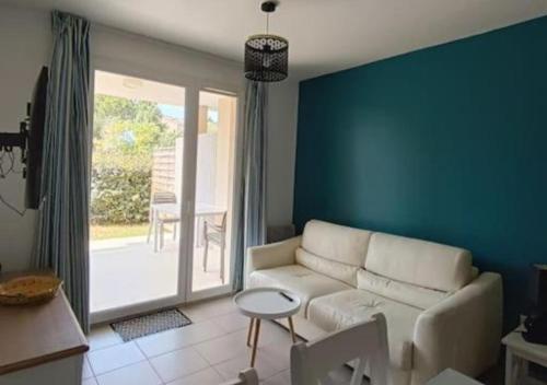uma sala de estar com um sofá branco e uma parede azul em L'argentière, proche plage,Résidence piscine, Tennis, parking em La Londe-les-Maures