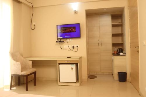 a room with a desk and a tv on the wall at Hotel Shyam Basera in Mathura