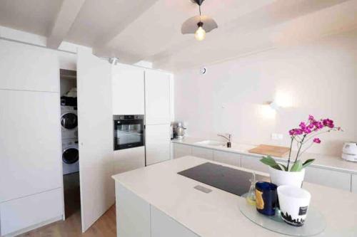 - une cuisine blanche avec un comptoir orné de fleurs violettes dans l'établissement Villa Lokeren avec petite vue mer, à Pornichet