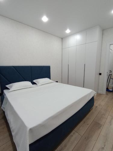 a bedroom with a large white bed with a blue headboard at 2-х комнатная квартира Гоголя 106 in Semey
