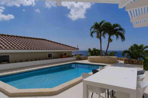 a pool with a table and chairs next to a house at NewVilla-Coral Estate-WalktoBeach-Private Pool-up to 16 Guests SeaView in Willibrordus