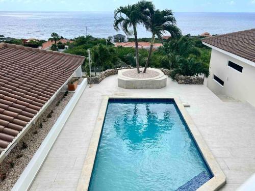 a swimming pool in front of a house with the ocean at NewVilla-Coral Estate-WalktoBeach-Private Pool-up to 16 Guests SeaView in Willibrordus