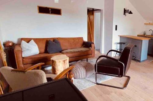 ein Wohnzimmer mit einem braunen Sofa und Stühlen in der Unterkunft stilvolles und komfortables Chalet mit Weitblick in Ebenfeld