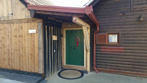an entrance to a wooden building with a green door at Holiday House Clavis in Dobrovnik