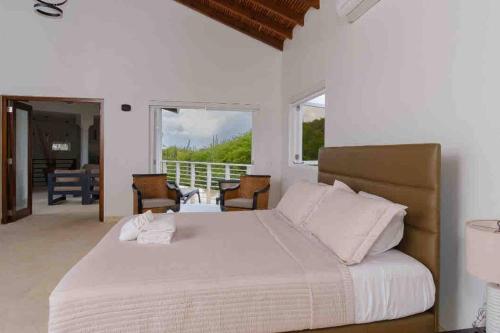 a bedroom with a large white bed and a balcony at NewVilla-Coral Estate-WalktoBeach-Private Pool-up to 16 Guests SeaView in Willibrordus