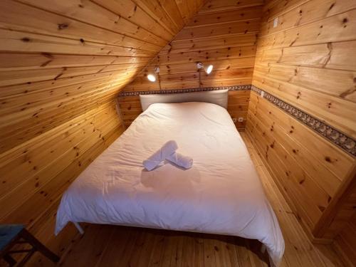 a bed in a wooden room with a bow on it at Chalet bois au coeur des Pyrénées ariégeoises in Soldeu lʼHospitalet