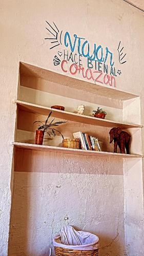 une étagère avec des livres et une pancarte sur un mur dans l'établissement Hostel Xitla, à Oaxaca