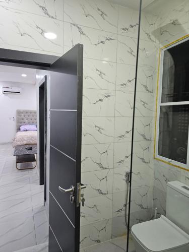 ein Badezimmer mit einem WC und einer Glastür in der Unterkunft Hencapservices 002HPS. in Agege